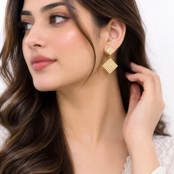 Elegant square crystal drop earrings worn by a woman, featuring a geometric double-square design with sparkling stones on a white background.