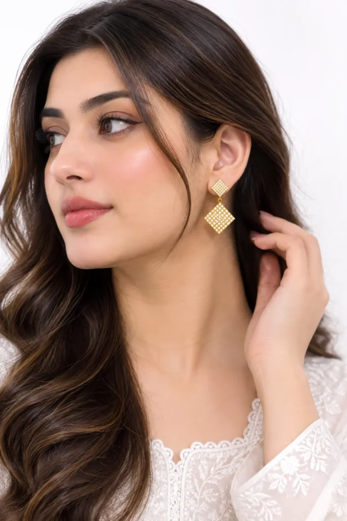 Elegant square crystal drop earrings worn by a woman, featuring a geometric double-square design with sparkling stones on a white background.